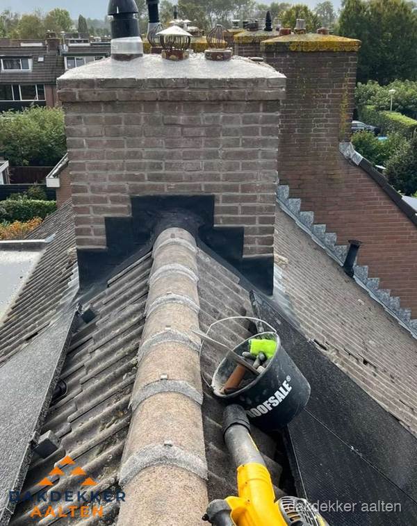 Schoorsteen met loodaansluiting en nokvorst op pannendak in Aalten Schoorsteen met loodaansluiting en nokvorst op pannendak in Aalten