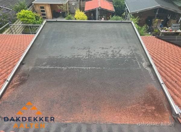 Verouderd plat dak met slijtage tussen schuine daken in Aalten Verouderd plat dak met slijtage tussen schuine daken in Aalten